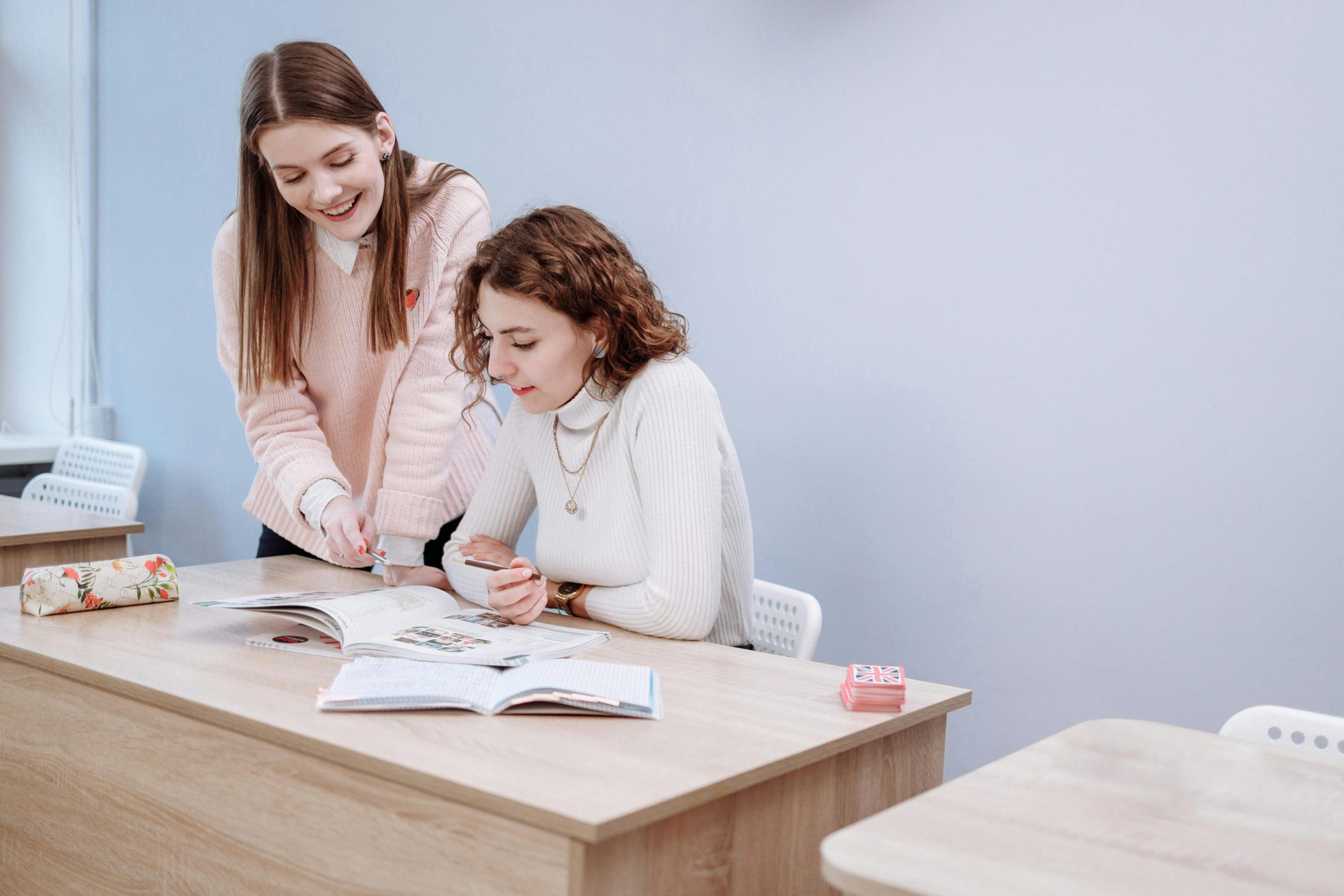 Two women collaborating on a study project in a classroom environment.