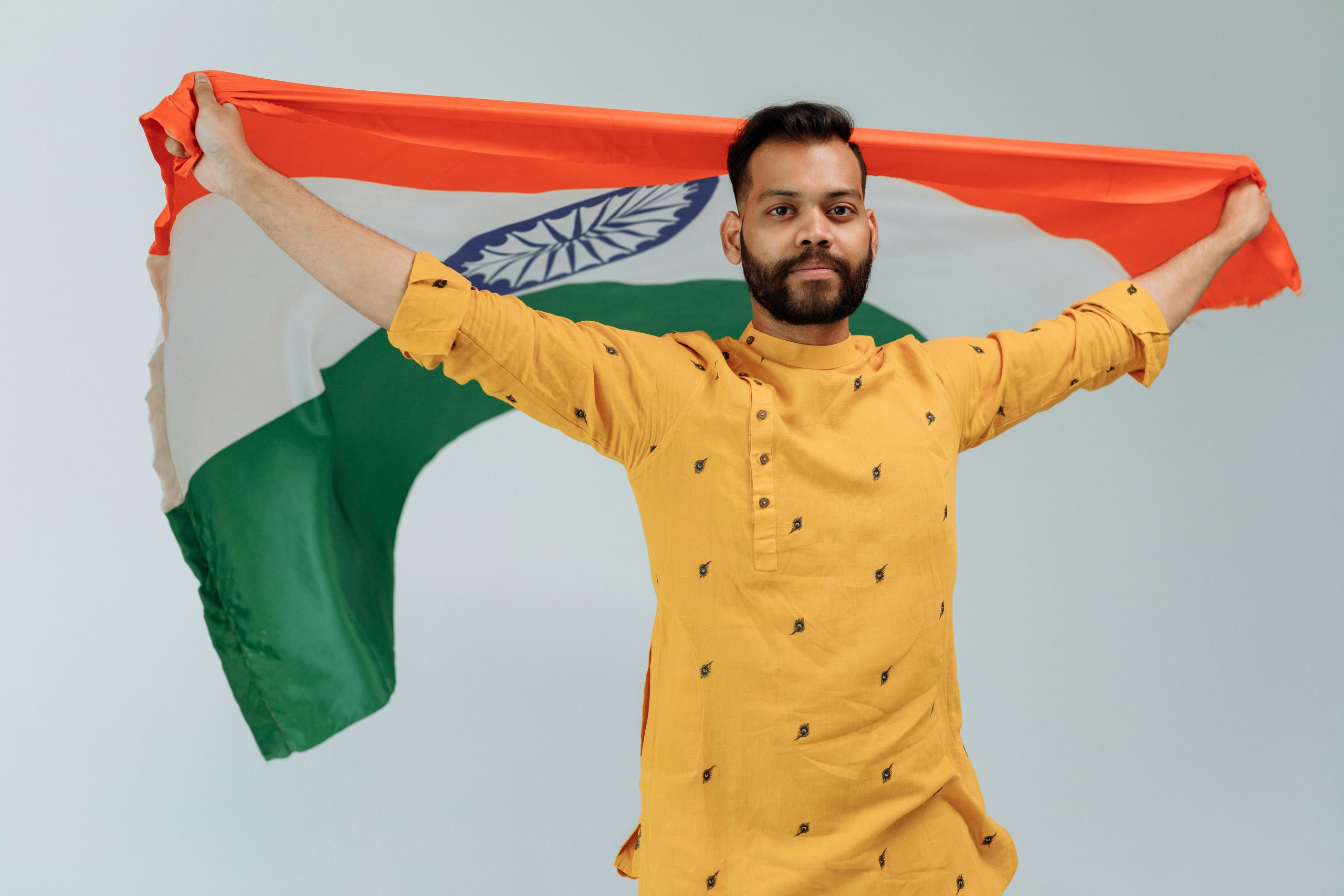 A serious man holds the Indian flag, showcasing pride and patriotism in a studio setting.