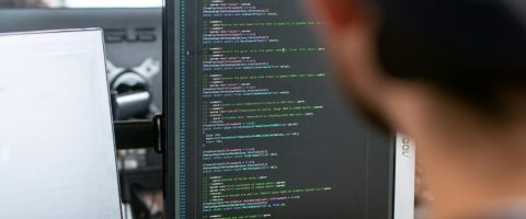 A male software engineer working on code in a modern office setting.