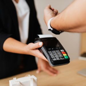 Person making a contactless payment using a smartwatch and a payment terminal.