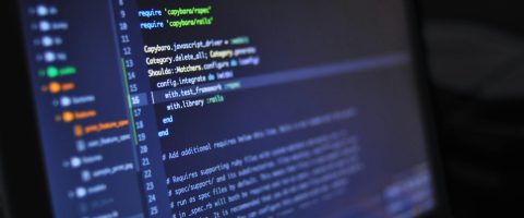 Close-up of a computer screen displaying programming code in a dark environment.
