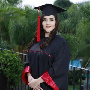 Young woman in graduation attire outdoors, celebrating academic achievement.